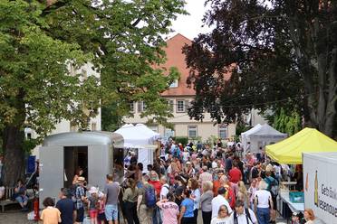 Jahresfest 2025 – Blick auf viele Personen, Informationsstände und Stände mit kulinarischen Angeboten im Schlosshof der Diakonie Stetten.