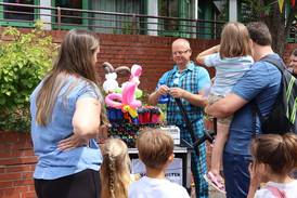 Jahresfest 2025 – Eine Personengruppe schaut einem Ballonkünstler zu. Jahresfest 2025 – Eine Personengruppe schaut einem Ballonkünstler zu.