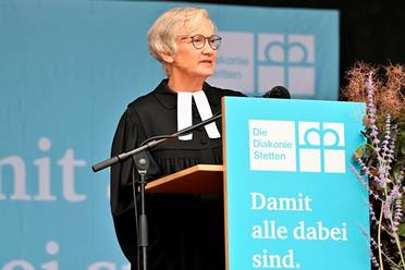 Jahresfest 2025 – Festgottesdienst – Die Leiterin Pfarramtliche Dienste, Ethik und Diakonisches Profil predigt auf der Bühne im Schlosspark.