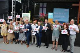 Jahresfest 2026 – Vor der Bühne stehen einige Personen nebeneinander und halten je ein weißes Schild mit rotem Kreuz in den Händen Jahresfest 2026 – Vor der Bühne stehen einige Personen nebeneinander und halten je ein weißes Schild mit rotem Kreuz in den Händen