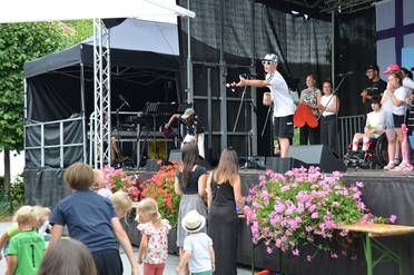 Jahresfest 2025 – Festfeier – Schülerinnen und Schüler führen bei der Festfeier auf der Bühne ihr Musikstück „Gemeinsam – Zusammen“ auf. Eine Person wirft kleine Gegenstände von der Bühne ins Publikum. 