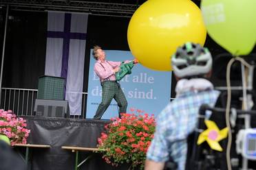 Jahresfest 2025 – Festfeier – Ein Zauberkünstler auf der Bühne unterhält die Besucher*innen mit einem großen gelben Ball.