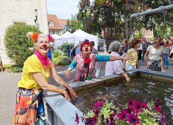 Ein bunt gekleidetes Damen-Duo unterhält die Besucher*innen beim Jahresfest.
