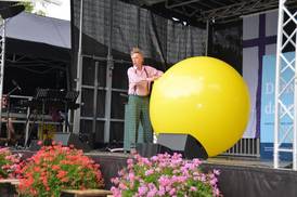 Jahresfest 2025 – Festfeier – Ein Zauberkünstler auf der Bühne unterhält die Besucher*innen mit einem großen gelben Ball. Jahresfest 2025 – Festfeier – Ein Zauberkünstler auf der Bühne unterhält die Besucher*innen mit einem großen gelben Ball.
